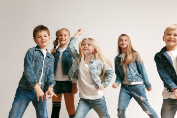 The portrait of cute little boy and girls in stylish jeans clothes looking at camera at studio